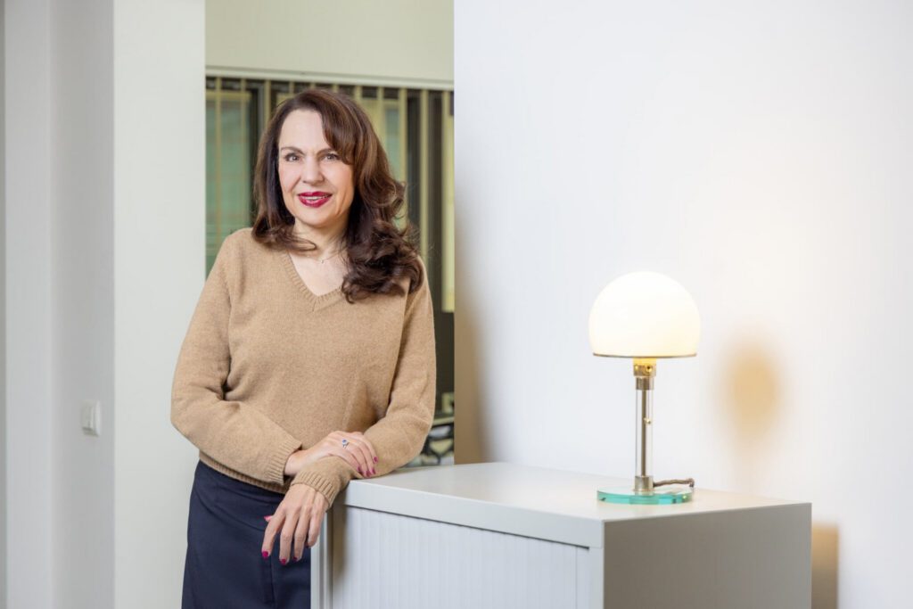 Anne Patsch stehend im Kanzleibüro neben einer modernen Design-Tischlampe